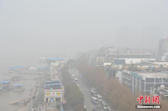 12月11日，武汉长江大桥一端隐匿在霾中，长江对岸的龟山电视塔见不到踪影。站在长江大桥上看去，位于长江南岸的黄鹤楼显得模糊。张畅 摄